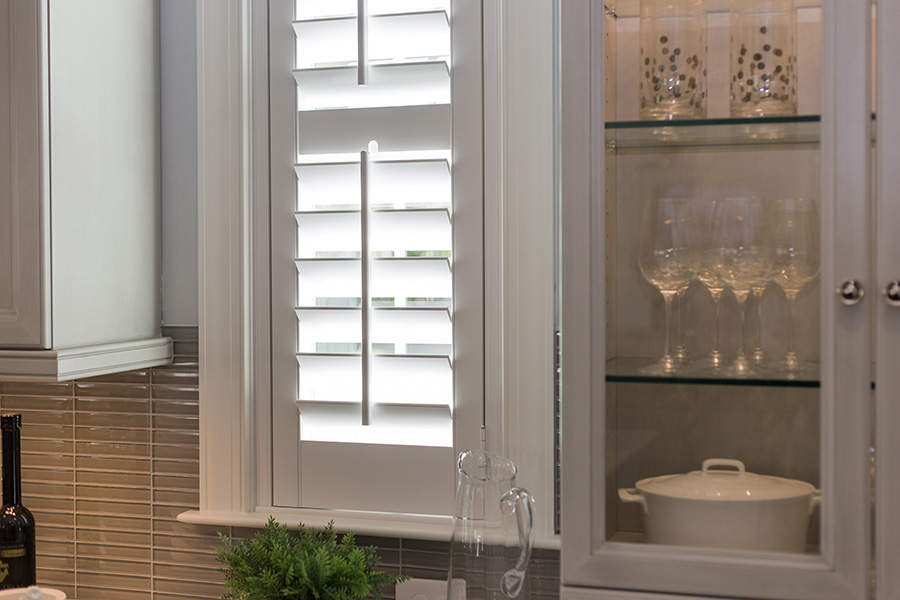 White Polywood shutters above a kitchen sink.