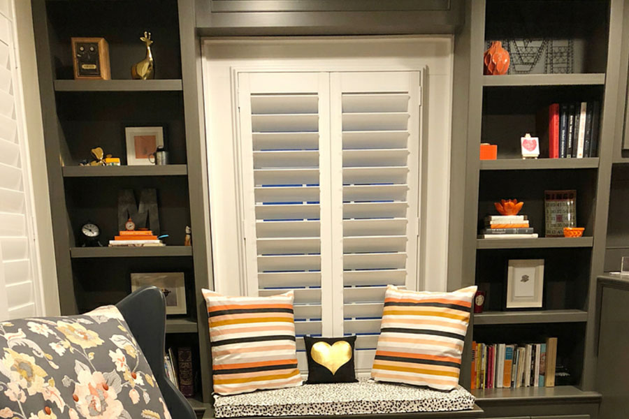White polywood shutters in a small library room at home.