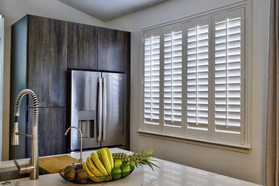 Homeowners use indoor window shutters in Austin when they want attractive and functional window treatments. Polywood shutters on a large kitchen window