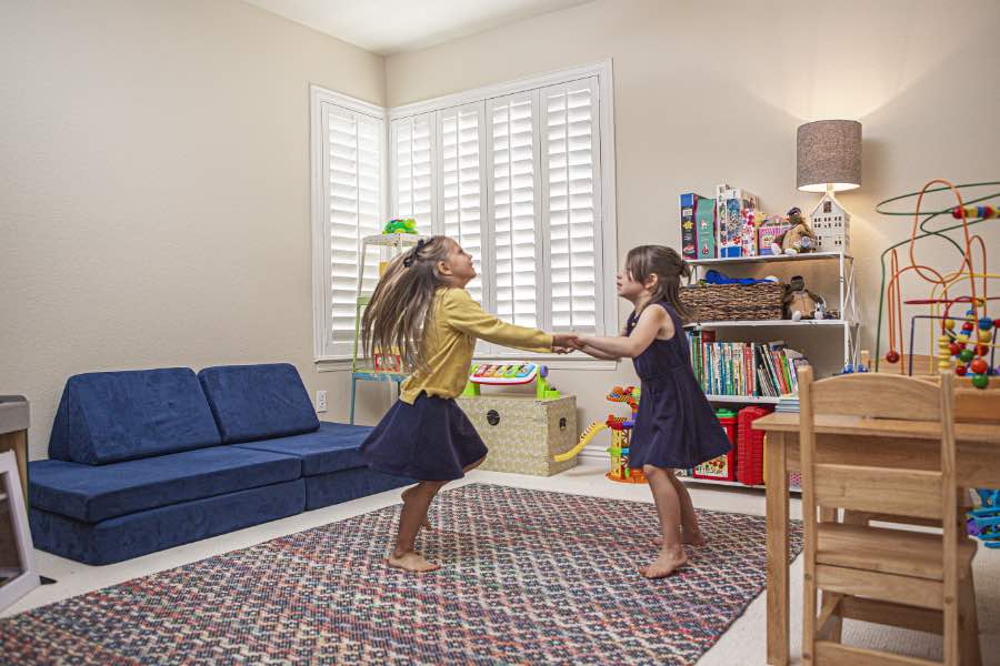 Choose Polywood shutters for durable, kid-friendly great room window treatments in Austin. Polywood shutters on multiple windows in a sitting area