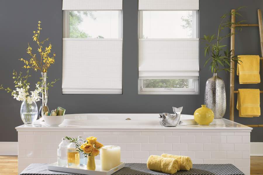 When you can't change a room's color, change the color of things in the room by adding vibrant decorative accents. A gray and white bathroom with several yellow decorative objects