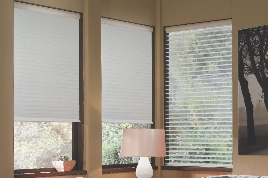 Opaque motorized window shades in Austin keep hot UV rays out of your home. Gray motorized sheer shades on corner windows next to gray furniture