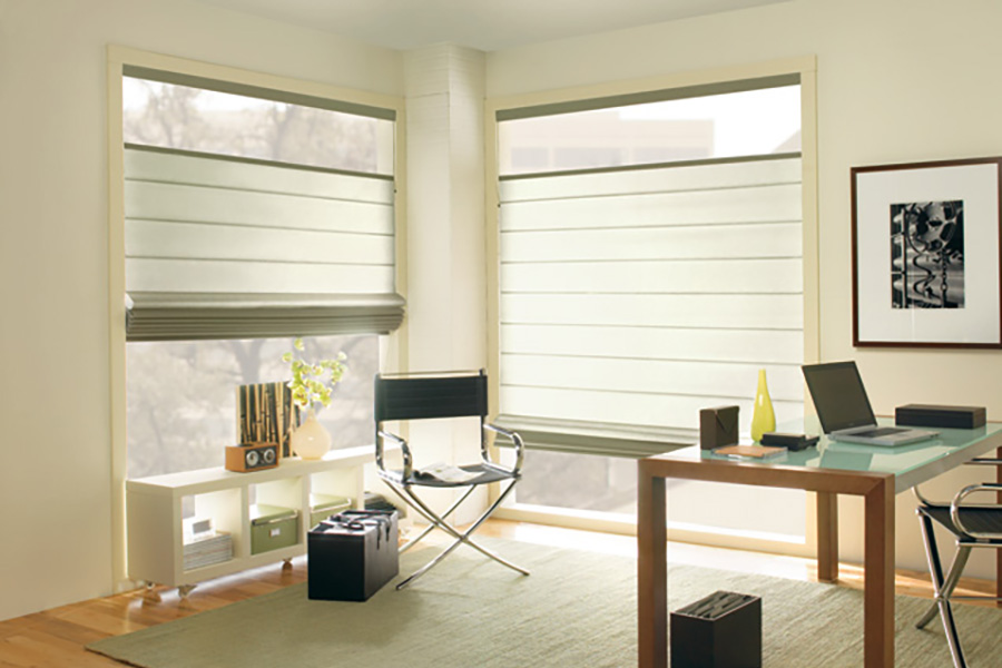 Available in a wide array of styles and colors, versatile Roman shades are suitable for nearly any room, including this home office. Modern Roman shades in a corner of an office.