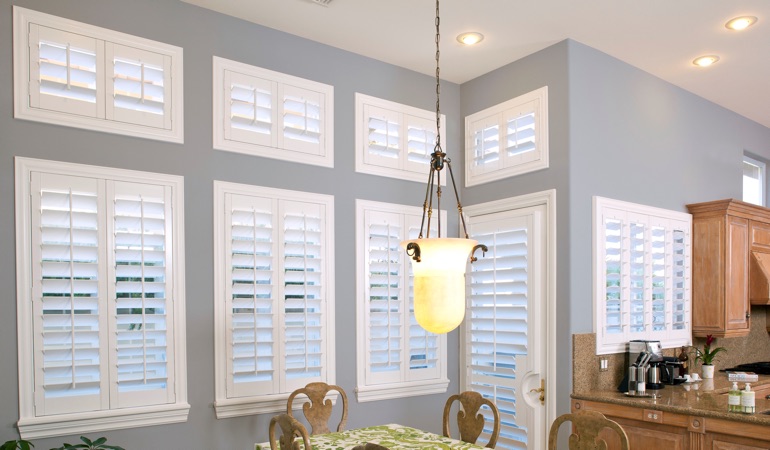 Plantation shutters can solve both sun glare and heat loss problems. White plantation shutters in kitchen