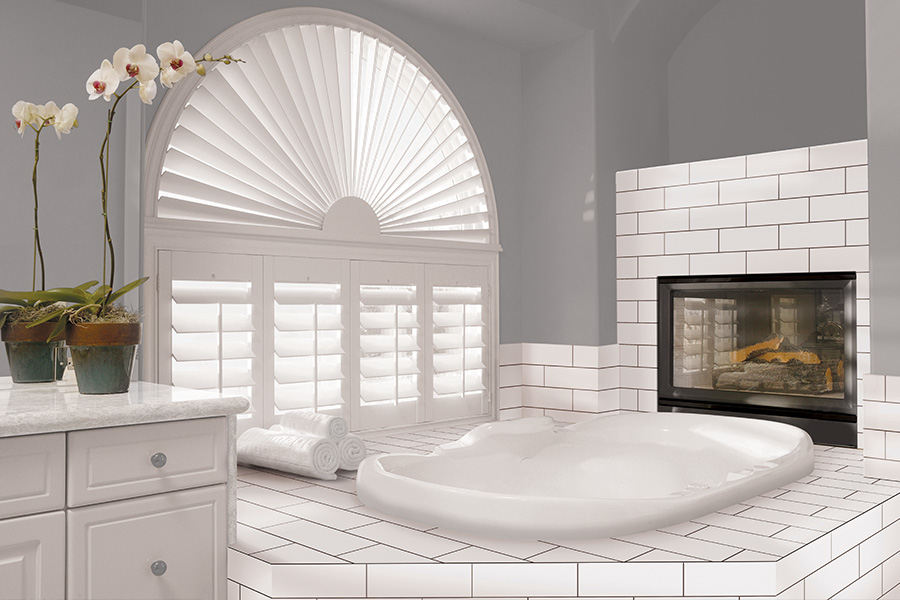 Explore our selection of window treatments for builders in Austin to find the perfect ones for your next construction project. White Polywood shutters on an arched bathroom window