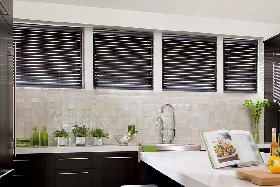 Choose custom Polywood faux wood blinds for your kitchen in Austin. Special shaped faux wood blinds in several windows above a sink.