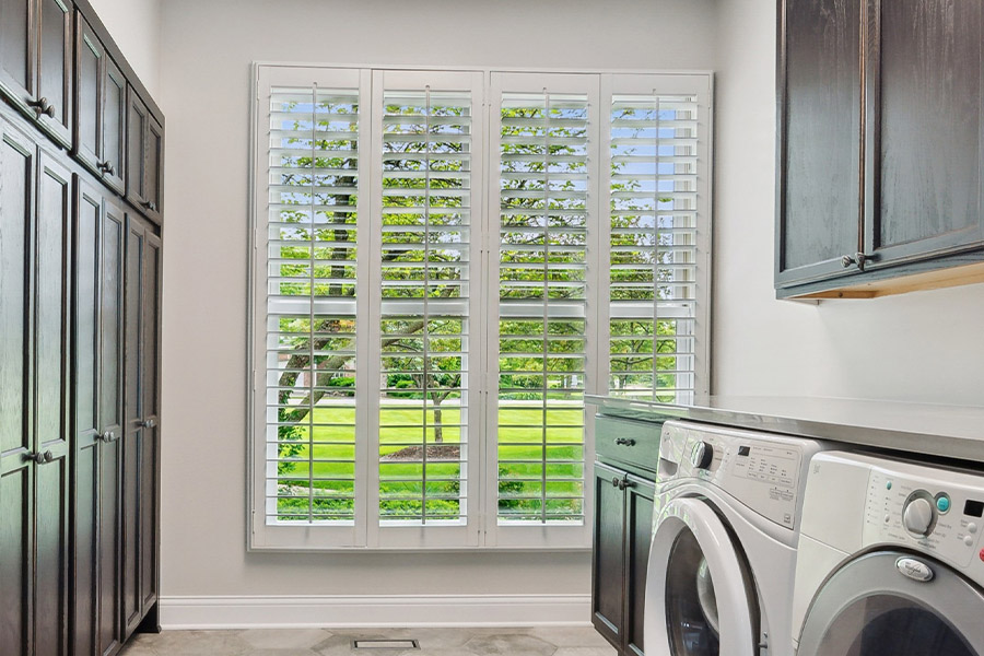 Find the perfect level of natural light for your Austin laundry room with interior shutters. White Polywood shutters letting light through a laundry room window