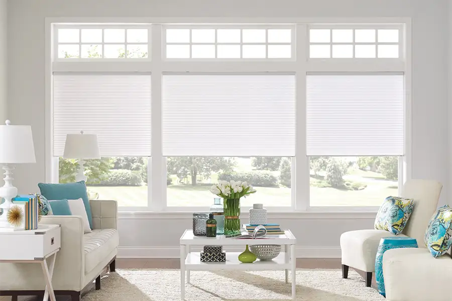 Insulating cellular shades can help keep cold air and hot UV rays from entering your Austin home. White cellular shades on windows in a white living room